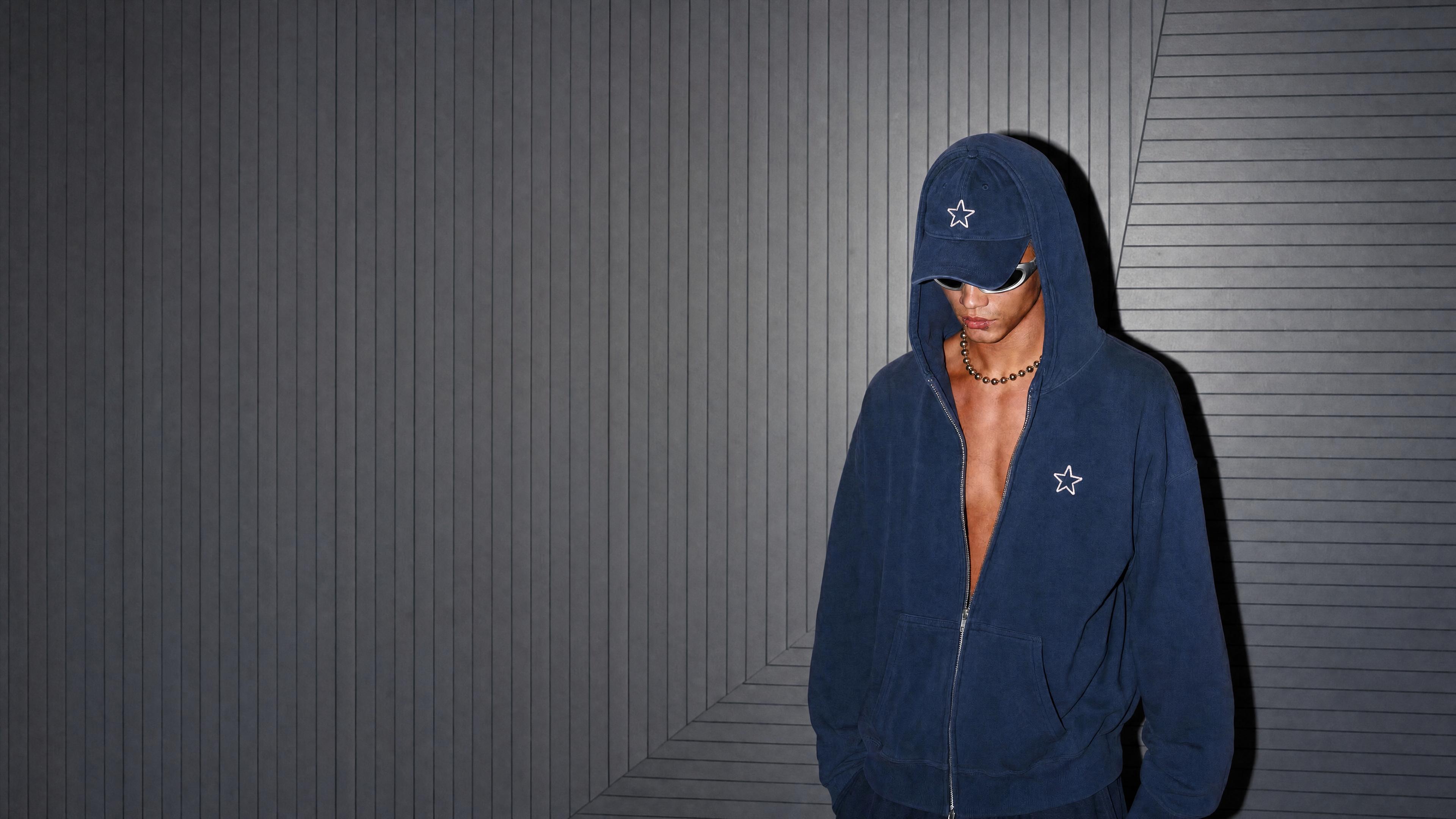 Elevenstoic creator wearing a navy hoodie and cap in a cinematic studio